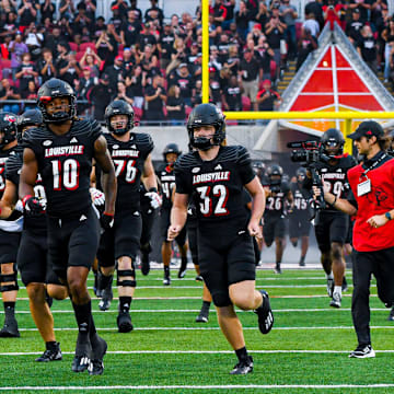 Louisville players running onto the field of L&N Stadium during pregame.