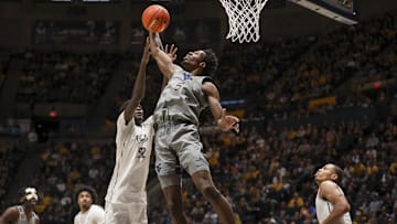 Mar 8, 2025; Morgantown, West Virginia, USA; West Virginia Mountaineers guard Toby Okani (5) grabs a rebound against UCF Knights center Moustapha Thiam (52) during the first half at WVU Coliseum. Mandatory Credit: Ben Queen-Imagn Images